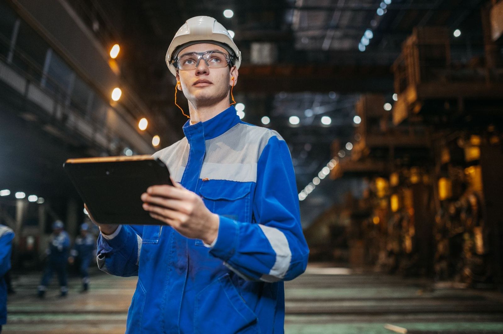 Field engineer in safety gear checking a tablet on an industrial site